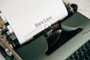 Close-up of an antique typewriter printing the word 'Review' on white paper.